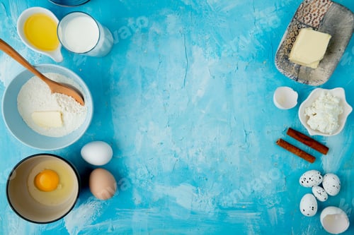 Preview: top view of foods as flour, butter, milk, cottage cheese, cinnamon and egg on blue background with