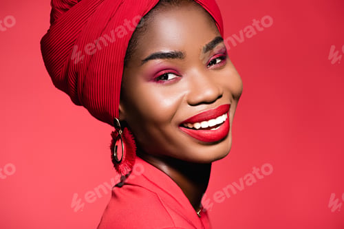 Preview: smiling african american young woman in stylish outfit and turban isolated on red