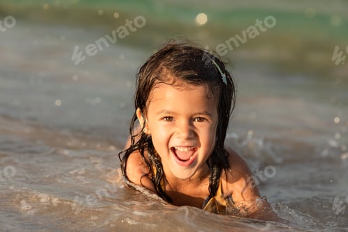 Vista previa: Retrato de verano de una niña feliz en la playa riendo y mirando a la cámara
