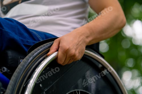 Preview: Close-up of the hand of a man with disabilities who rides a wheelchair in city park