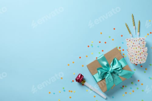 Visualização: Caixa de presente com laço e acessórios de aniversário em fundo azul, vista superior