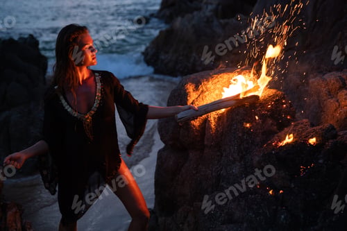 Preview: Mysterious woman on the beach at dusk and holding a flaming torch