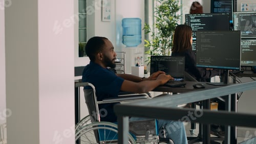 Preview: African american IT engineer with disability typing code in it development agency