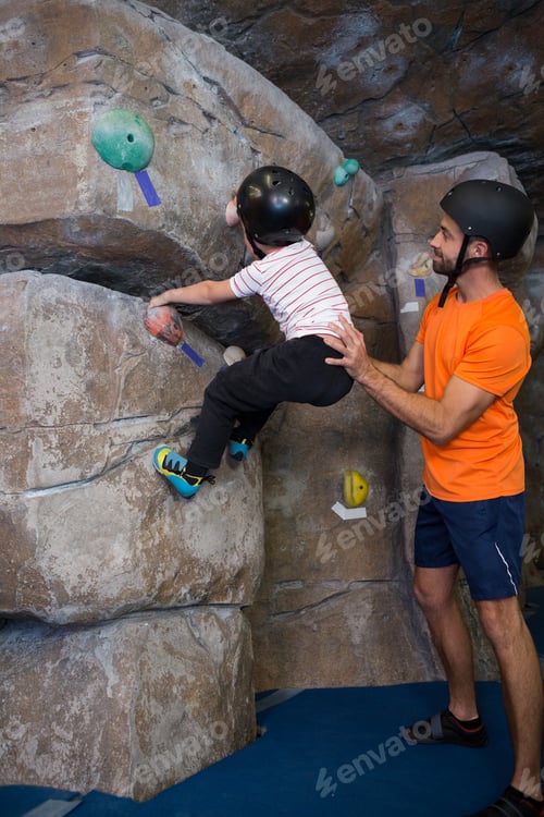 Preview: Trainer assisting boy in rock climbing