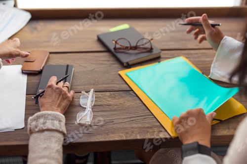 Preview: Two senior women sitting at table with phones and documents