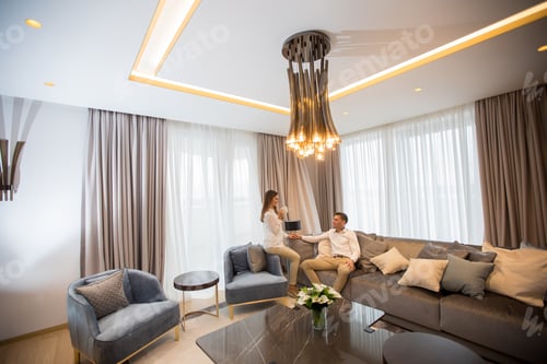 Preview: Young couple relaxing and talking with coffee cups in the luxurious room