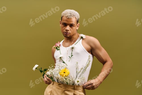 Preview: Young man showcases floral style in trendy tank top within vibrant studio setting