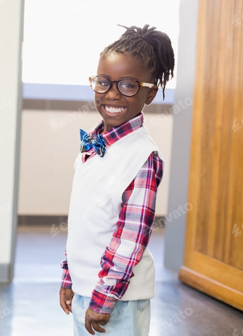 Preview: Smiling schoolboy wearing glasses and bow tie, standing confidently in hallway