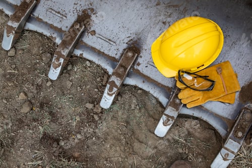 Preview: Hardhat, Gloves and Protective Glasses Resting on Bulldozer Bucket Abstract