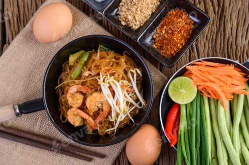 Preview: Padthai shrimp in a black bowl with eggs and Seasoning on wooden table.