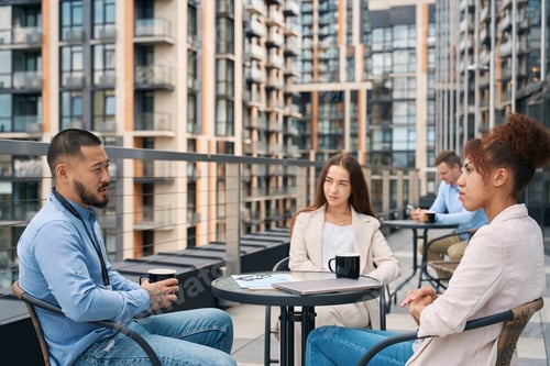 Preview: Young corporate employee communicating with his coworkers during coffee break