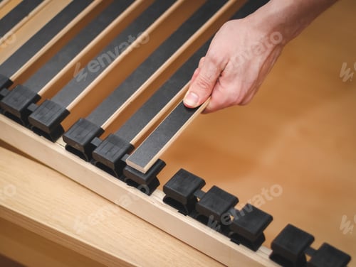 Preview: The hands of a caucasian young man are connecting black wooden slats with plastic