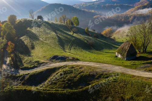 Preview: Aerial view of autumn countryside mountain with wooden houses, thatched roof and dirt road