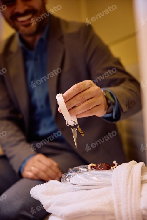 Preview: Close up of man holding bracelet with a key in dressing room at health spa.