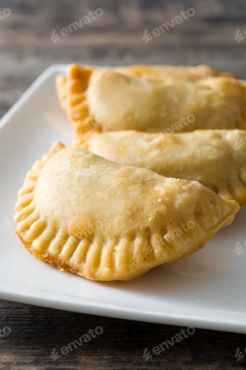 Preview: Delicious empanadas resting on white plate on wooden table