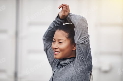 Preview: Smiling young Asian woman stretching before going for a run