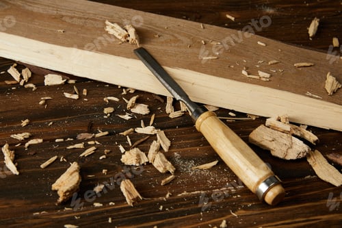 Preview: close up view of wooden plank and pieces with chisel on brown table