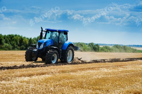 Preview: blue tractor in motion at field working with plow