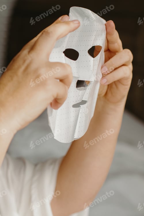 Preview: Caucasian female applying skincare sheet mask on face for rejuvenation