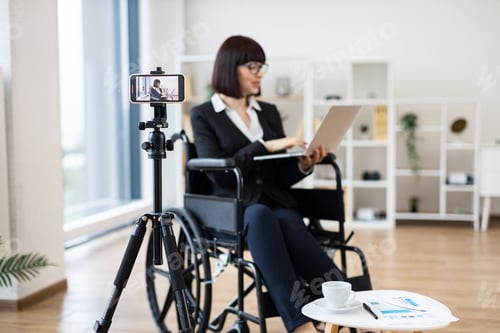 Preview: Businesswoman in wheelchair vlogging about workplace with laptop and camera