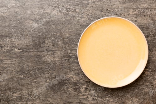 Preview: Top view of empty orange plate on cement background. Empty space for your design