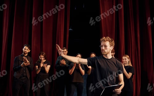 Preview: Group of actors in dark colored clothes on rehearsal in the theater