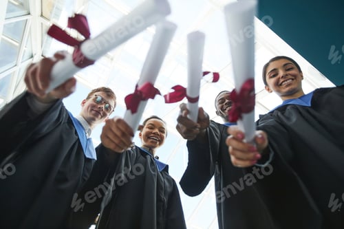 Preview: Graduates holding diplomas to camera