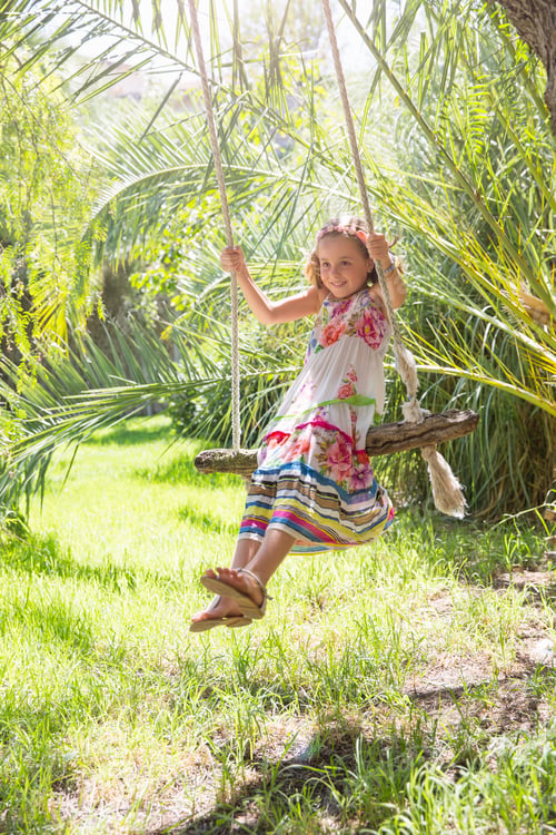 Preview: Girl sitting swinging on tree swing in garden