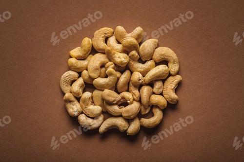 Preview: top view of pile of cashew nuts on brown background