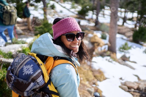 Preview: Cheerful portrait of an African American woman looking at camera smiling, standing in a snowy forest