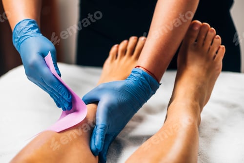 Preview: Waxing - Beautician Removing Unwanted Hair from Female Leg with Wax Strips