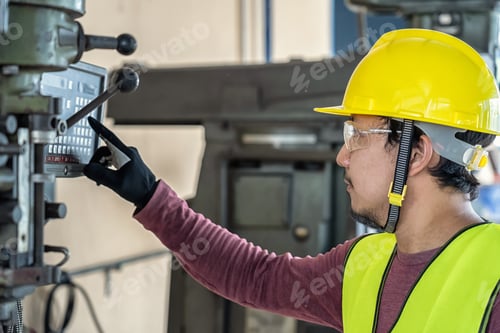 Preview: Asian factory engineer in safety suit operating and pressing the professional machinist