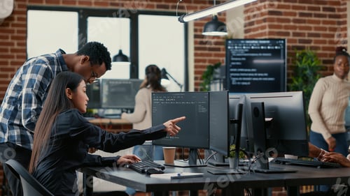 Preview: Mixed team of software developers analyzing source code pointing at screens comparing algorithm