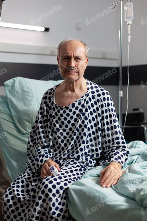 Preview: Portrait of sad, unwell senior man sitting on the edge of hospital bed