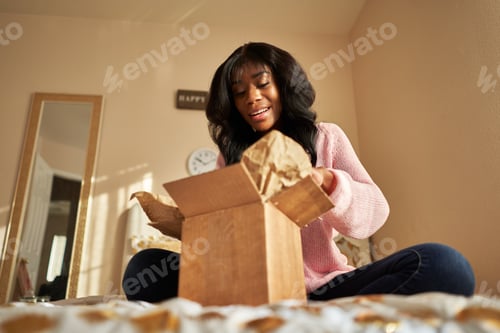 Preview: african american woman opening box on bed