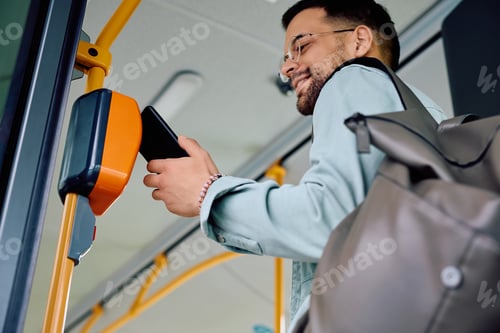Preview: Below view of man using app on mobile phone while entering in public transport.
