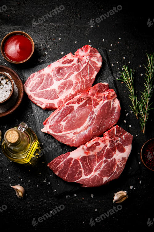 Preview: Raw pork steak on a stone board with tomato sauce, rosemary and spices.