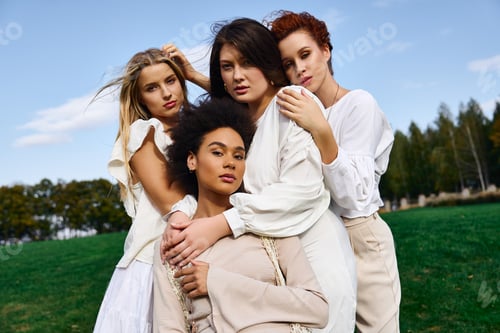 Preview: Four fashionable women embrace confidence and style under a sunny sky in a lush park