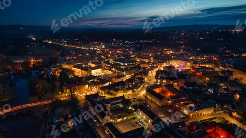 Preview: Aerial view of a vibrant town at dusk with illuminated streets.