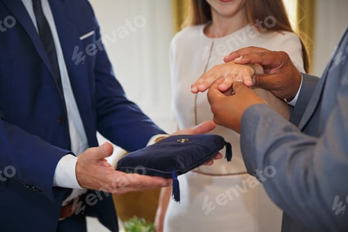Preview: Mixed race couple holding hands and exchanging wedding rings