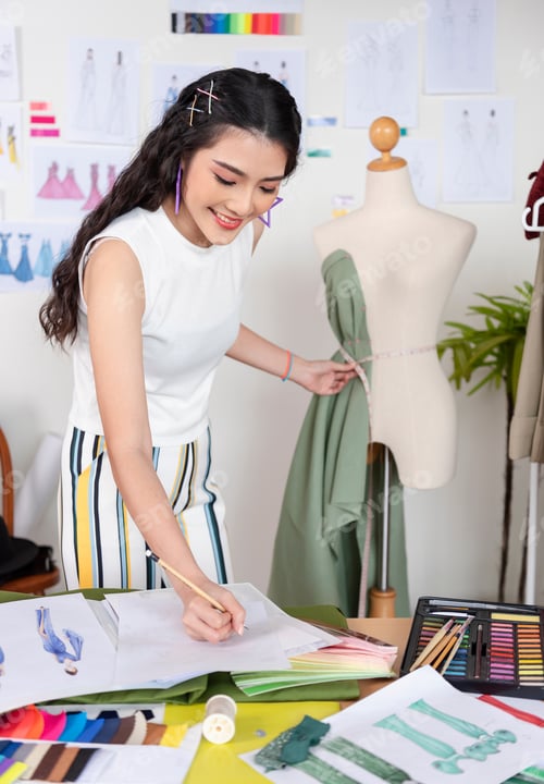 Preview: Asian tailor woman working on clothes in tailoring atelier, beautiful young female fashion designer