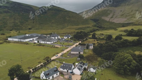 Preview: Arran whiskey distillery aerial. Road in green mountains valley. Scottish village with houses, camp
