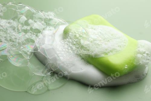 Preview: Soap bar with foam on green background, closeup