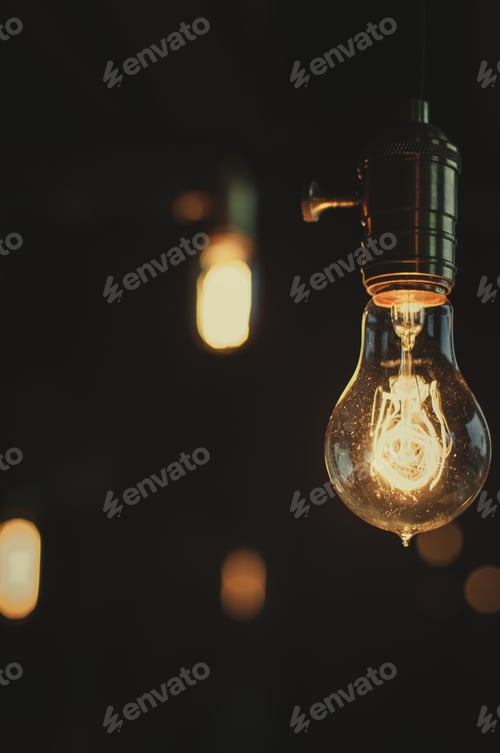 Preview: Illuminated Vintage Style Bulb Against a Dark Background