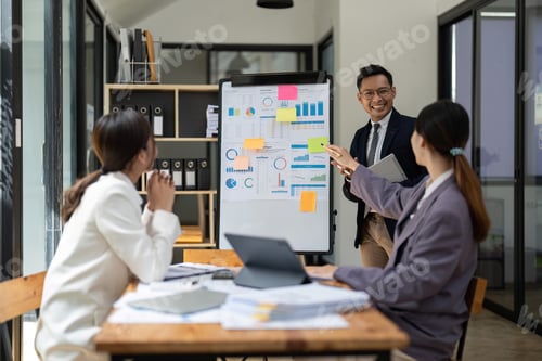Preview: Business adviser explaining business plan strategy on flipchart to colleagues, male coach or