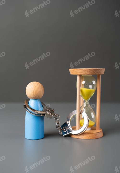 Preview: A man is handcuffed to an hourglass.