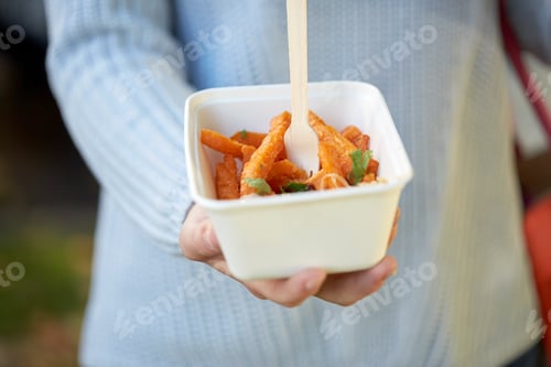 Preview: close up of hand holding plate with sweet potato