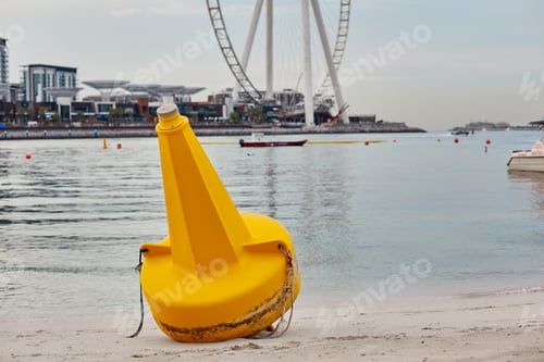 Preview: A bright yellow buoy lies on the shore against the background of the island Bluewater
