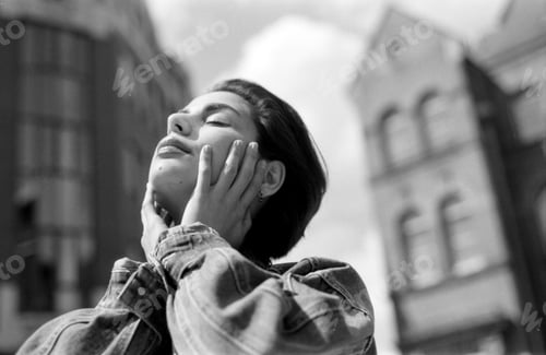 Preview: Young woman enjoying sunlight in urban setting, grainy black and white analog photo