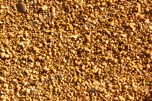 Preview: Mediterranean shoreline pebble beach. Natural golden tone textured background. Nobody